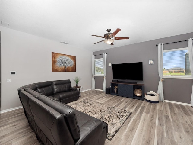 living room with a wealth of natural light, light hardwood / wood-style flooring, and ceiling fan