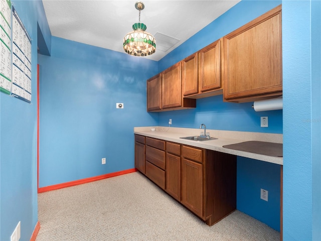 kitchen featuring sink, a notable chandelier, pendant lighting, and light carpet