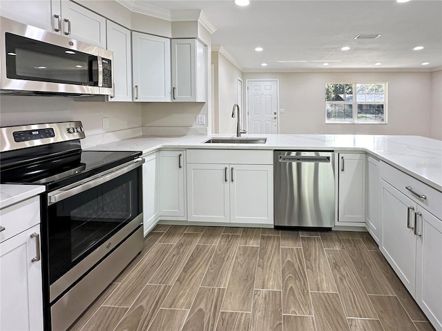 kitchen featuring light hardwood / wood-style flooring, sink, kitchen peninsula, appliances with stainless steel finishes, and white cabinetry