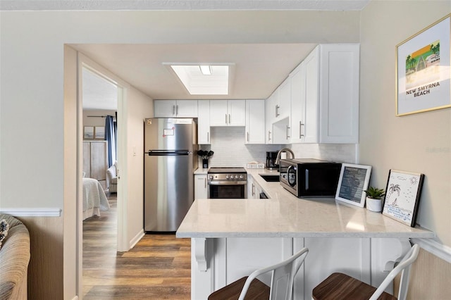 kitchen with light stone counters, a peninsula, a breakfast bar area, and appliances with stainless steel finishes