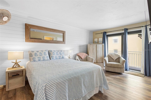 bedroom with access to outside, wood walls, and wood finished floors