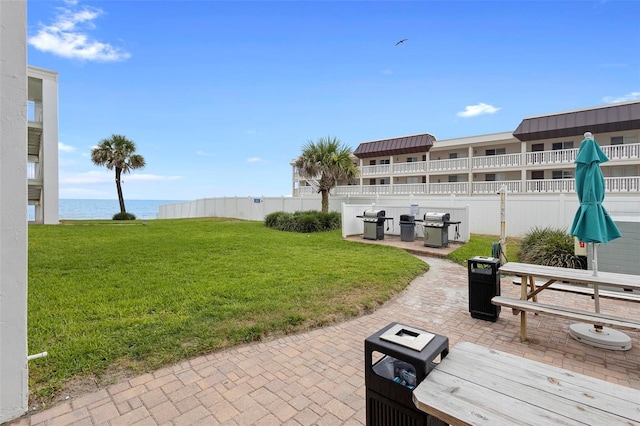 view of patio with a grill, fence, and a water view