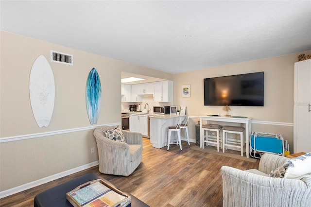 living room featuring wood finished floors, visible vents, and baseboards