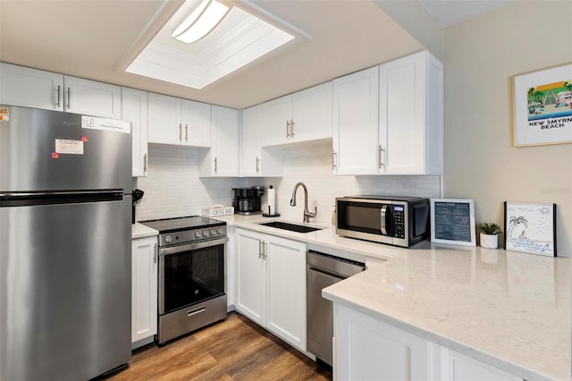 kitchen with appliances with stainless steel finishes, white cabinetry, backsplash, and a sink