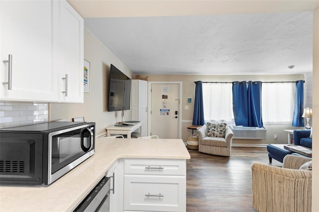 kitchen with white cabinets, black microwave, light countertops, open floor plan, and a peninsula