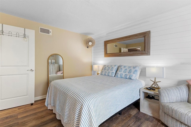 bedroom featuring wooden walls, visible vents, wood finished floors, and baseboards