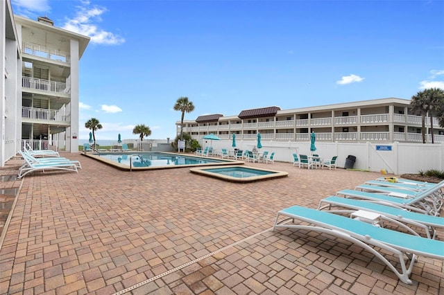 pool with fence, a patio area, and a hot tub