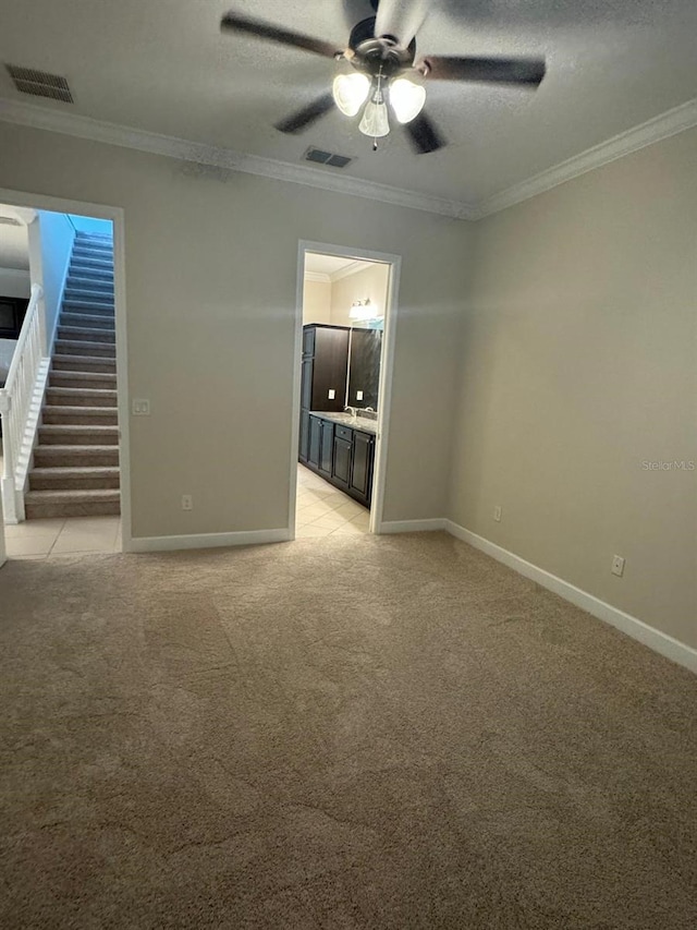 empty room featuring ceiling fan, light colored carpet, a textured ceiling, and ornamental molding