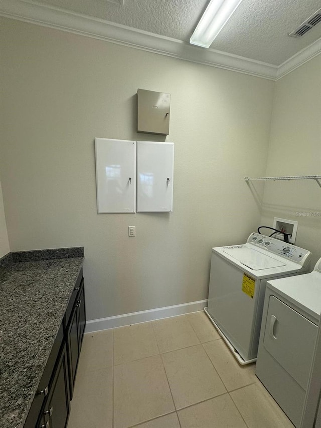 laundry room with cabinets, independent washer and dryer, crown molding, a textured ceiling, and light tile patterned floors