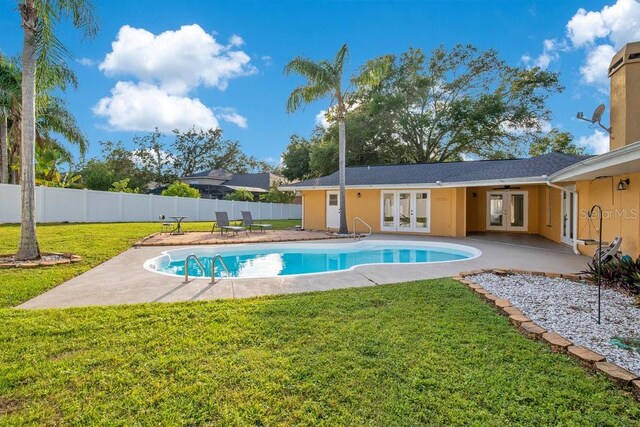 view of swimming pool featuring french doors, a patio, and a lawn