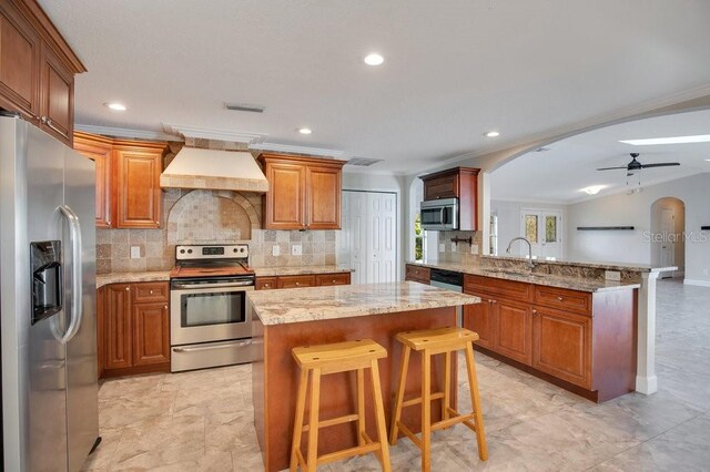 kitchen featuring appliances with stainless steel finishes, sink, kitchen peninsula, ceiling fan, and custom range hood