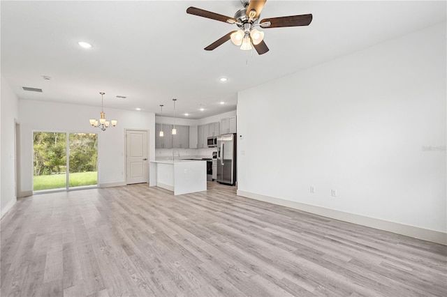 unfurnished living room featuring ceiling fan with notable chandelier, light wood-type flooring, and sink