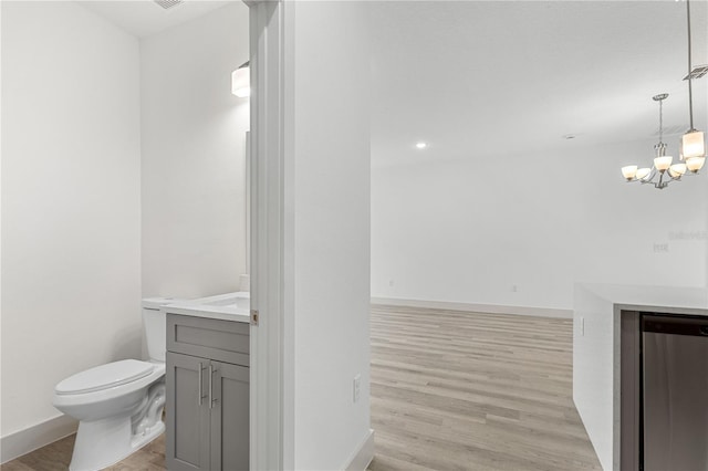 bathroom with hardwood / wood-style floors, vanity, toilet, and a notable chandelier