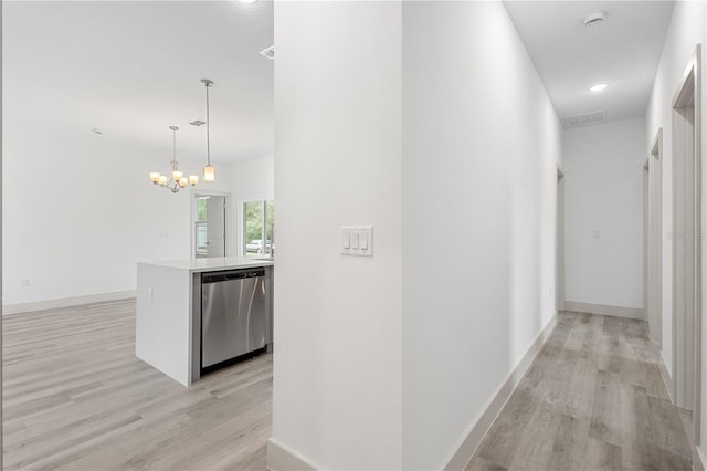 hallway with light hardwood / wood-style flooring and a notable chandelier