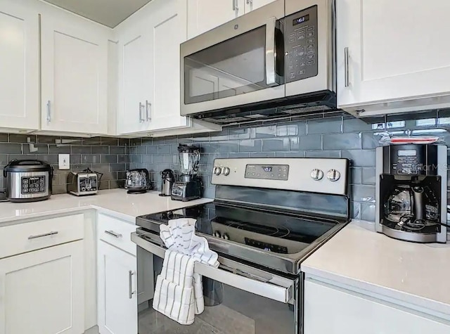 kitchen with white cabinetry, stainless steel appliances, and tasteful backsplash