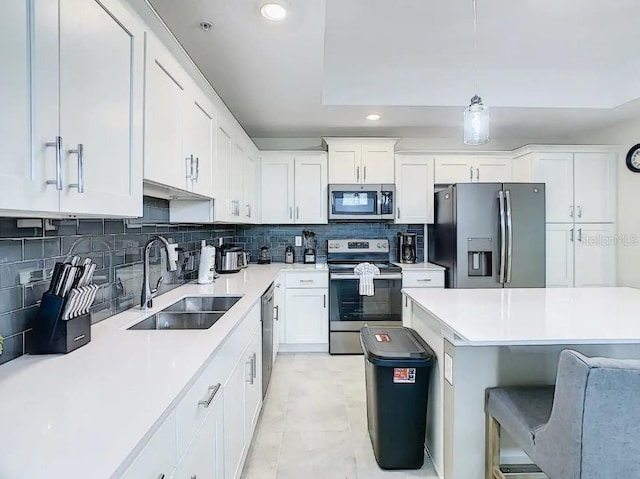 kitchen with white cabinetry, stainless steel appliances, sink, and decorative light fixtures