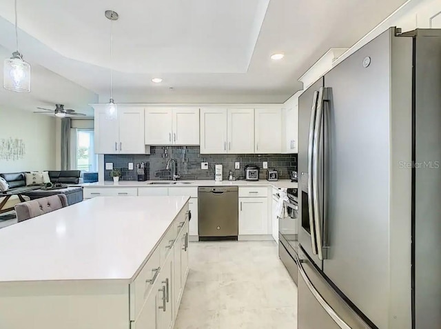 kitchen featuring sink, white cabinets, decorative light fixtures, appliances with stainless steel finishes, and tasteful backsplash