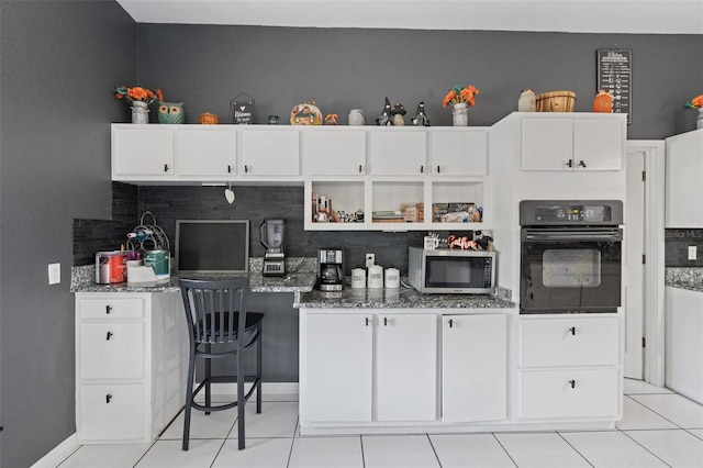 kitchen featuring decorative backsplash, black oven, and dark stone counters