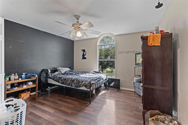 bedroom with dark wood-type flooring, ceiling fan, and a textured ceiling