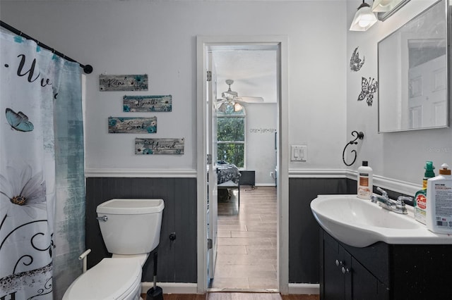 bathroom featuring ceiling fan, hardwood / wood-style flooring, toilet, vanity, and curtained shower