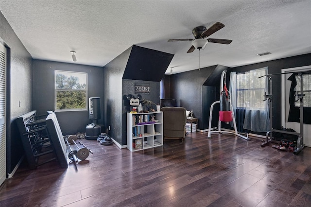 workout area featuring a textured ceiling, dark hardwood / wood-style floors, and ceiling fan