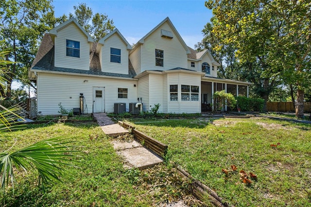 rear view of property featuring a sunroom, a lawn, and central AC unit