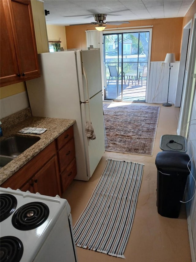 kitchen featuring ceiling fan, sink, light stone counters, and white appliances