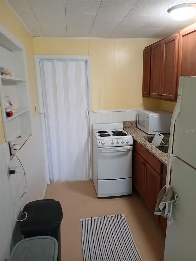 kitchen with built in features, light stone counters, white appliances, and sink