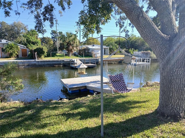 view of dock featuring a lawn and a water view