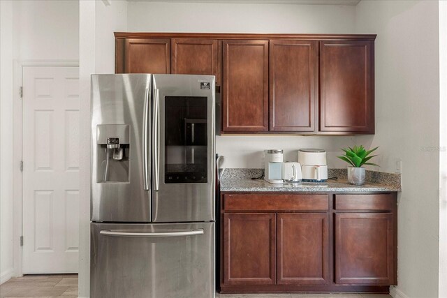 1909 Cayman Cove Cir, Saint Cloud, FL 34772 - kitchen featuring light stone countertops, light wood-style flooring, baseboards, and stainless steel fridge with ice dispenser