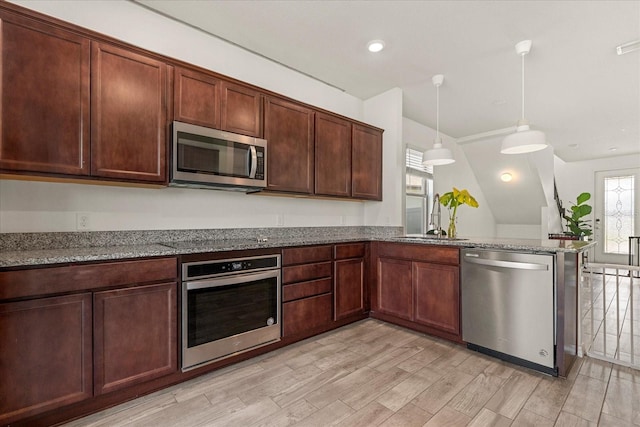 kitchen featuring light hardwood / wood-style flooring, kitchen peninsula, dark stone countertops, decorative light fixtures, and appliances with stainless steel finishes