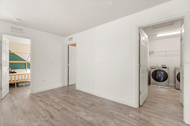 laundry room featuring a textured ceiling, washer and clothes dryer, and light wood-type flooring