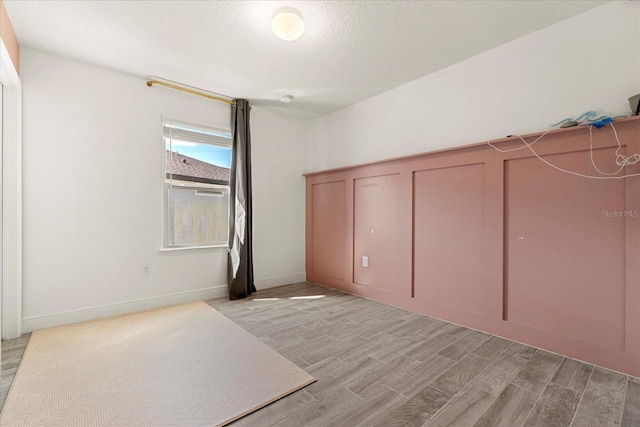 unfurnished bedroom with a textured ceiling and light hardwood / wood-style flooring