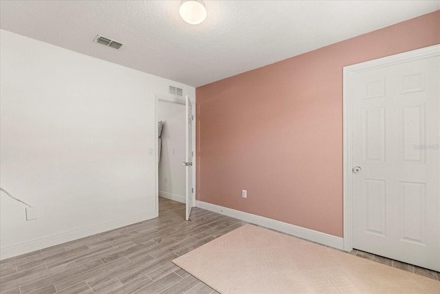 empty room with light hardwood / wood-style floors and a textured ceiling