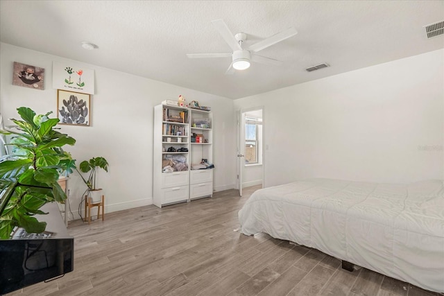 bedroom featuring light hardwood / wood-style flooring, a textured ceiling, and ceiling fan