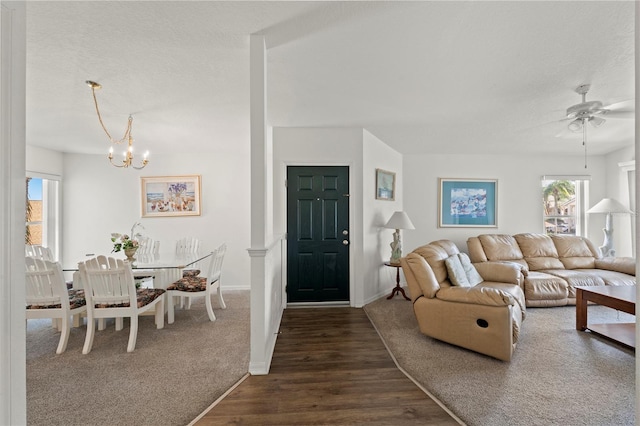 living room featuring ceiling fan with notable chandelier, a textured ceiling, and dark hardwood / wood-style flooring