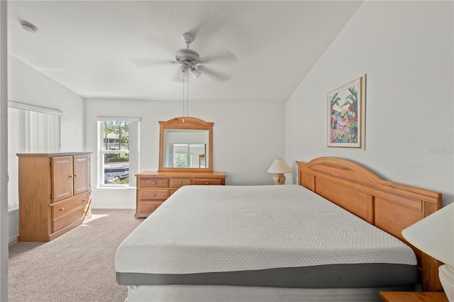 bedroom featuring ceiling fan, light colored carpet, a textured ceiling, and vaulted ceiling