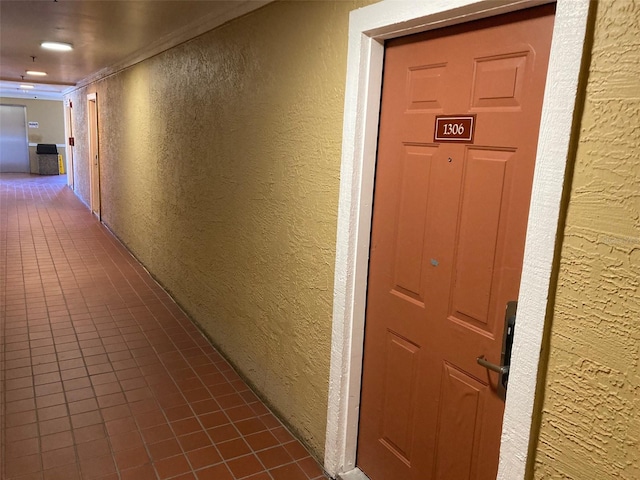 corridor with crown molding and dark tile patterned floors