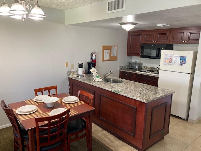 kitchen featuring sink, a textured ceiling, decorative light fixtures, light stone counters, and white refrigerator