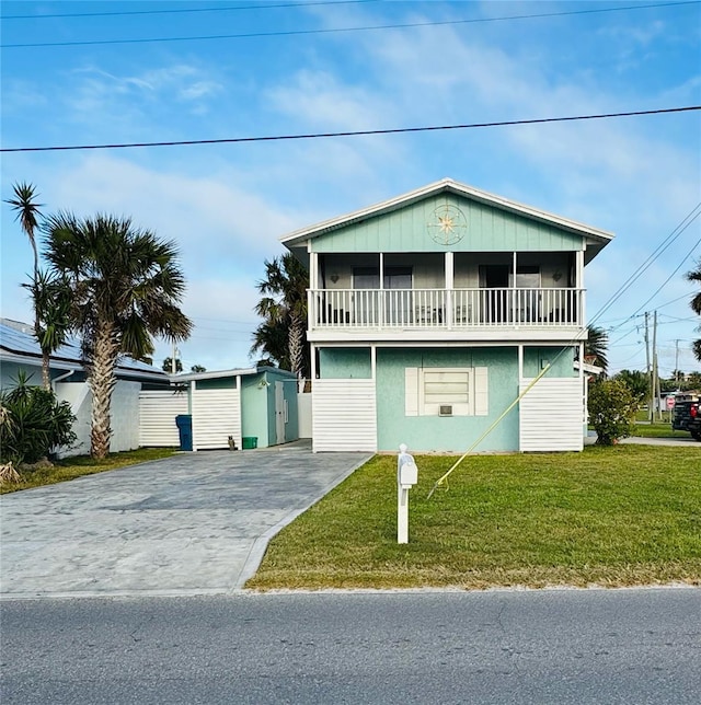 view of front of property with a storage unit, a balcony, and a front yard