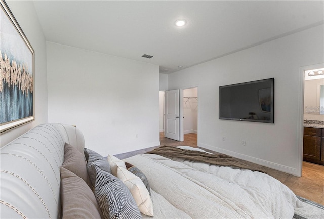 tiled bedroom with a walk in closet, ensuite bathroom, and a closet