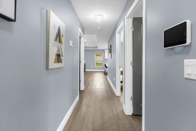 corridor featuring light hardwood / wood-style flooring and a textured ceiling