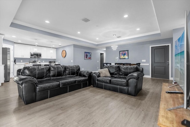 living room with a tray ceiling and light hardwood / wood-style floors