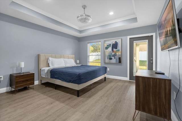 bedroom featuring light wood-type flooring and a raised ceiling