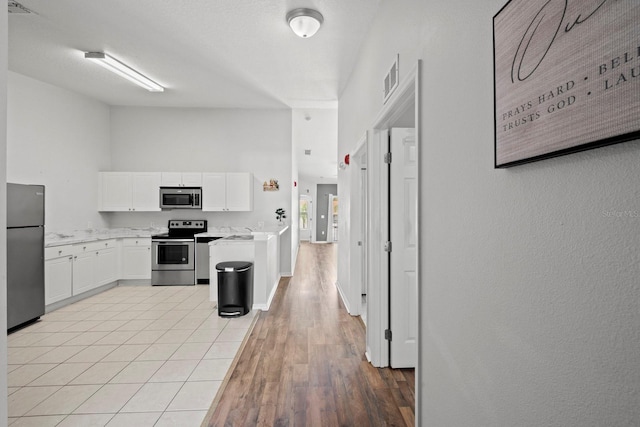 kitchen featuring appliances with stainless steel finishes, white cabinetry, sink, and light hardwood / wood-style floors