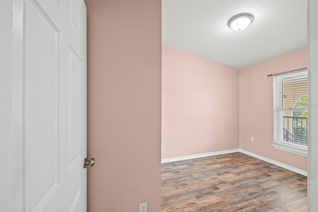 unfurnished room featuring light wood-type flooring and a textured ceiling