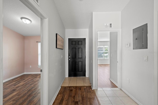 entryway featuring electric panel, light hardwood / wood-style floors, and a textured ceiling