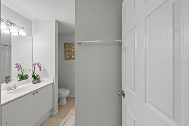 bathroom featuring vanity, tile patterned flooring, toilet, and a textured ceiling