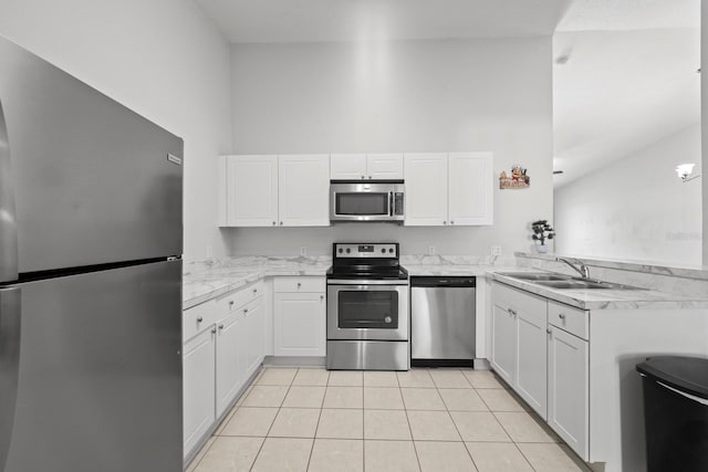 kitchen with light tile patterned flooring, kitchen peninsula, white cabinetry, appliances with stainless steel finishes, and a high ceiling