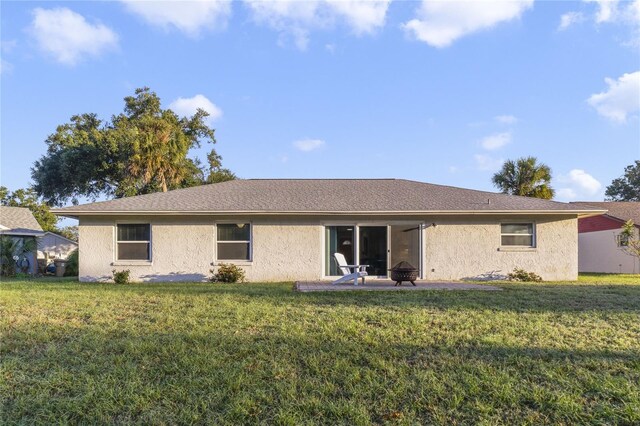 back of property with a lawn, a patio area, and an outdoor fire pit